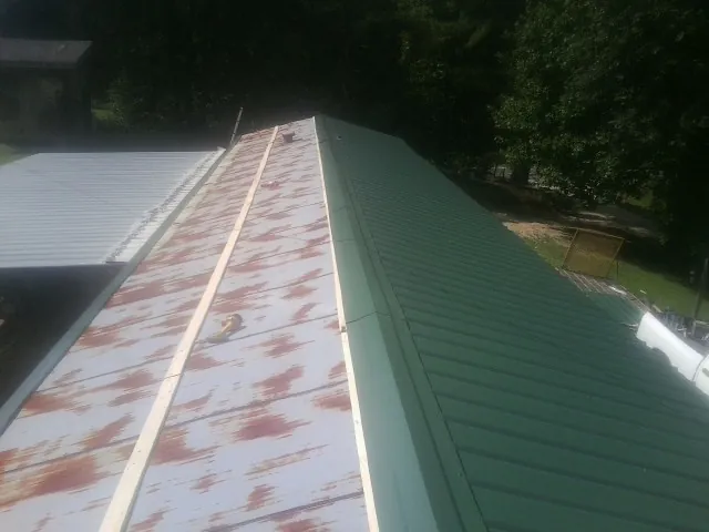 Old rusted panels beside newly installed green metal roofing — Wind Damage Roof Repair by Roofing Brothers in Lake Toxaway
