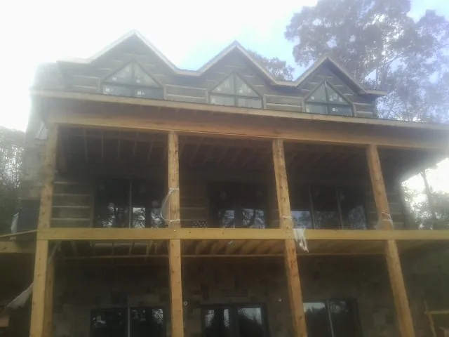 Dormers and porch framing on a large log home under construction — Roof Coating work by our crew in Lake Toxaway