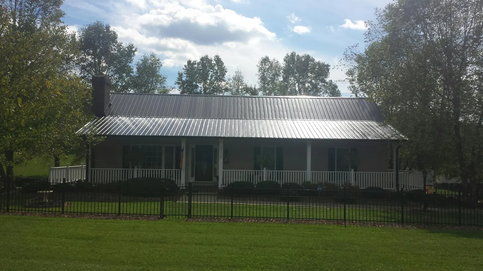 Gray metal roof on a brick ranch with a full width front porch — Gutter Guard Installation work by our crew in Lake Toxaway