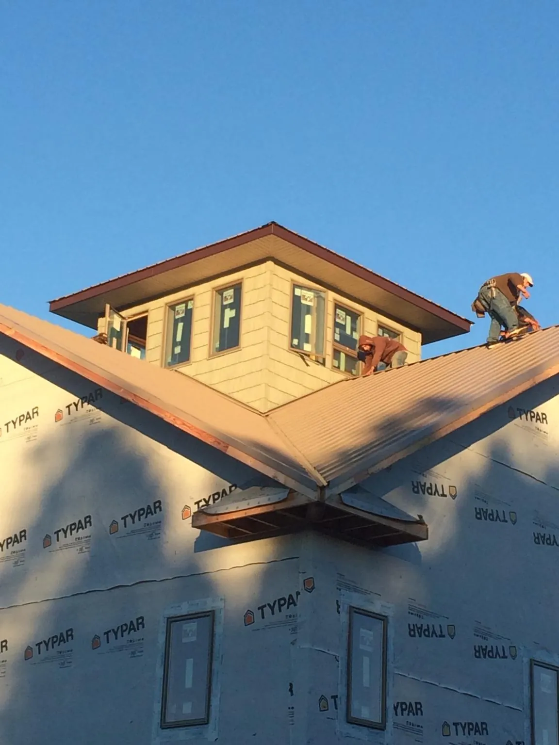 Roofers working around a rooftop cupola on a new metal roof at sunset — Roof Waterproofing in Lake Toxaway by Roofing Brothers